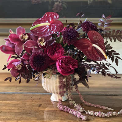Magenta floral arrangement in a white vase with trailing blooms