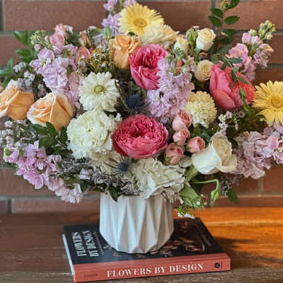 Mixed bouquet of pastel roses, gerbera daisies, and stock in a white vase