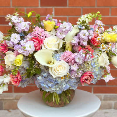 Mixed pastel bouquet in a round vase with roses, calla lilies, and hydrangeas