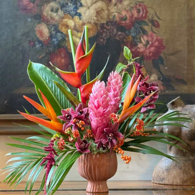 Tropical flower arrangement in a pink vase with pink and orange blooms