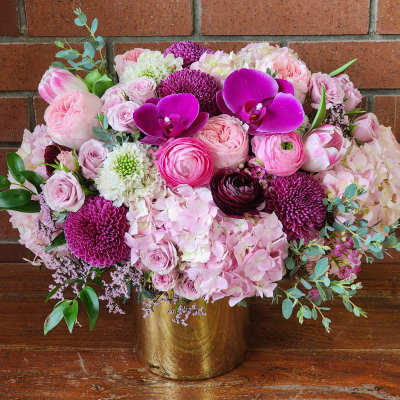Pink and purple floral arrangement in a gold vase