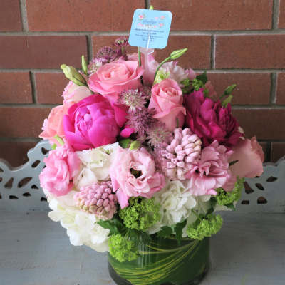 Pink and white flower arrangement with roses, peonies and hydrangeas in a glass vase with leaf wrap