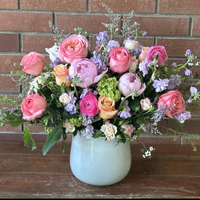 Pink and lavender flower arrangement in a pale blue vase