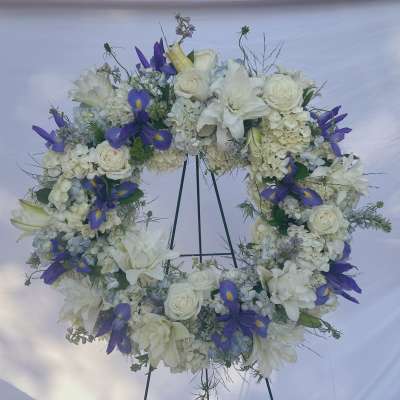 White and purple floral wreath on a stand