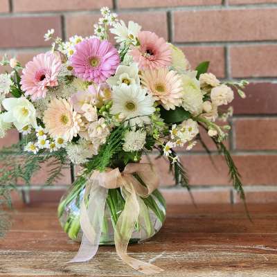 Pastel mixed bouquet in a round glass vase with a ribbon