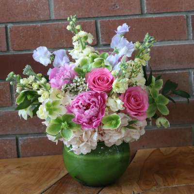 Pink and white flower arrangement in a green glass vase