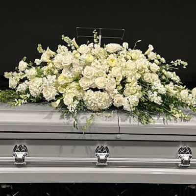 White floral casket spray on a silver casket