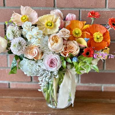 Mixed bouquet of pastel and bright flowers in a clear glass vase