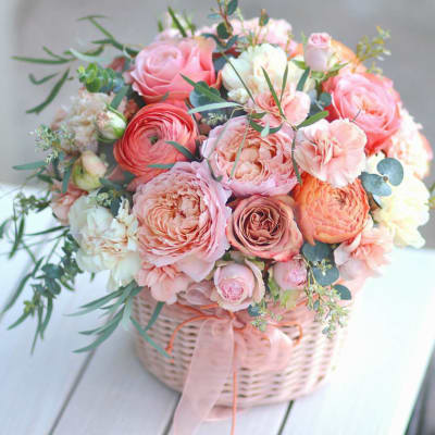 Pink and peach rose bouquet in a wicker basket with ribbon