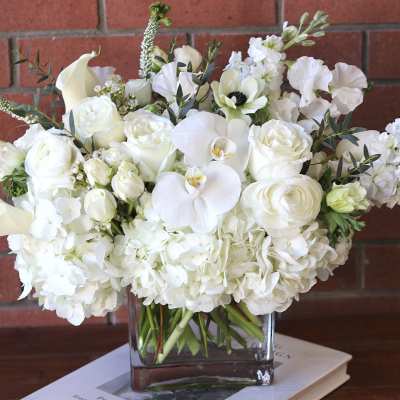 White floral arrangement in a clear square vase