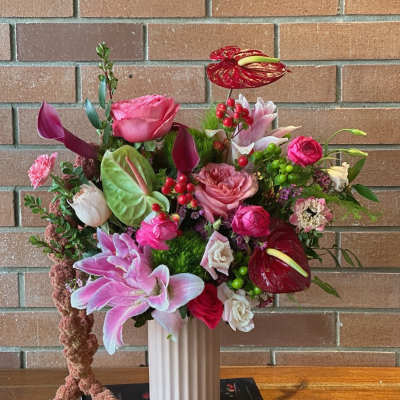 Mixed pink and red floral arrangement in a white vase