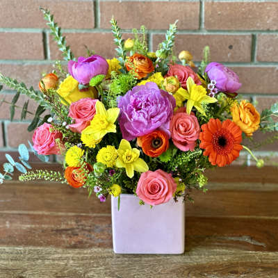 Colorful mixed bouquet in a square lavender vase