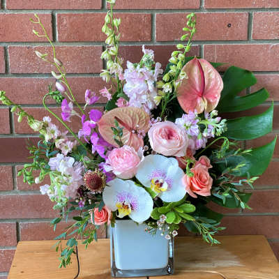 Pink and white floral arrangement in a square glass vase