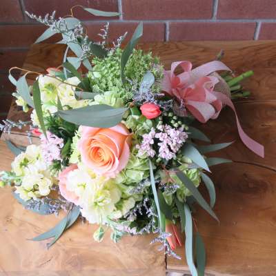 Bouquet of peach roses and pale flowers with a pink ribbon