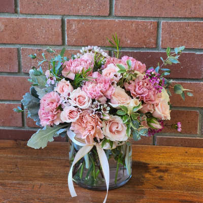 Pink and blush bouquet in a glass vase with a white ribbon