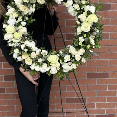 Large white floral wreath on a black stand