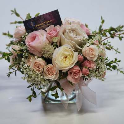 Pink and cream rose bouquet in a glass vase with a ribbon
