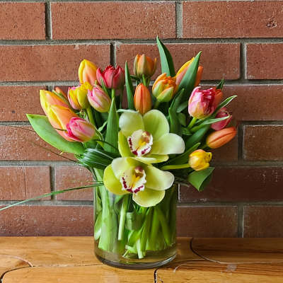 Bouquet of tulips and orchids in a glass vase