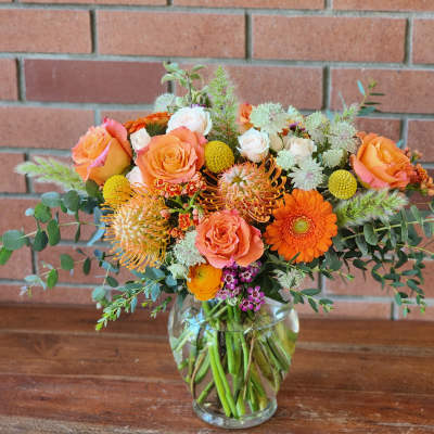 Bouquet of orange and peach flowers in a clear glass vase