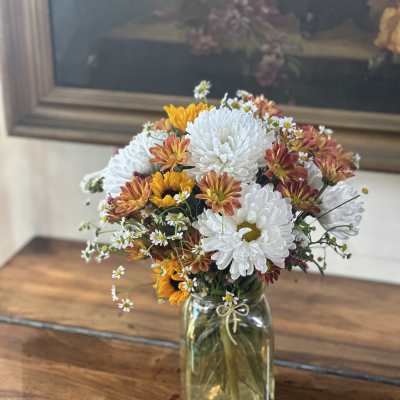 Bouquet of white and orange chrysanthemums in a glass jar