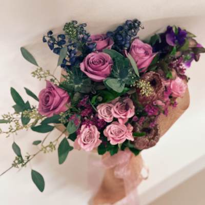 Bouquet of pink and purple roses with greenery and a pink ribbon