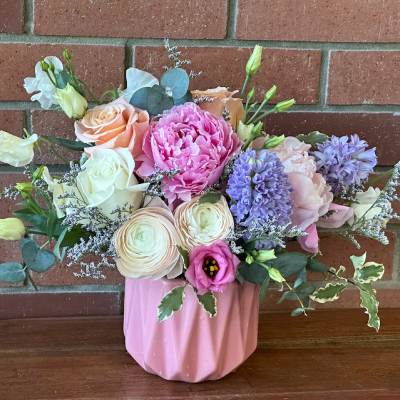 Pastel arrangement of roses, peonies, ranunculus and hyacinth in a pink ceramic vase