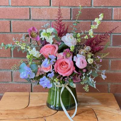 Pink and white floral arrangement in a glass vase with a ribbon