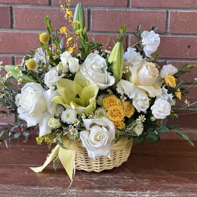 Basket arrangement of white and yellow flowers with a ribbon