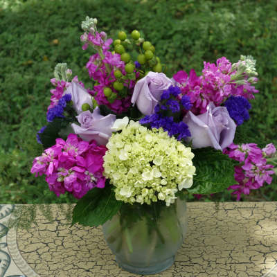 Lavender roses and pink-purple flowers in a glass vase