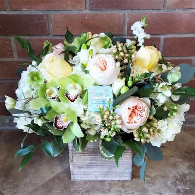 Mixed bouquet of pale roses, orchids, and white blooms in a wooden box