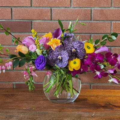 Mixed bouquet in a clear glass vase with purple, pink, and yellow flowers
