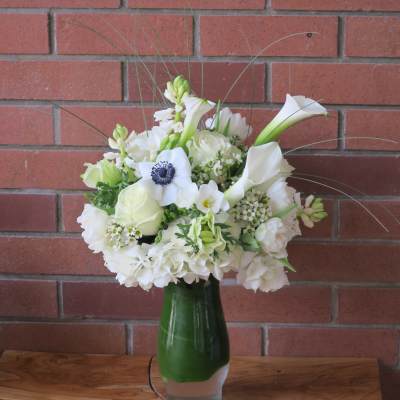 White floral arrangement in a green glass vase