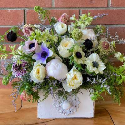 Mixed bouquet of white, lavender, and pink flowers in a white box
