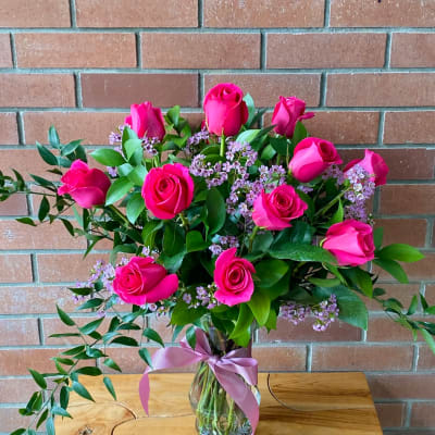 Pink roses arranged in a glass vase with a ribbon