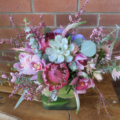 Pink and purple floral arrangement in a green vase with succulents