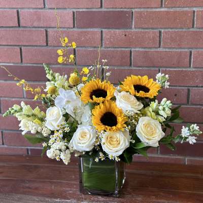 Sunflowers and white roses arranged in a square glass vase