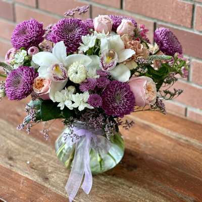 Bouquet of purple and pink flowers in a glass vase with a ribbon
