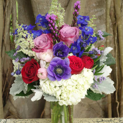 Mixed bouquet of roses, anemones, and hydrangea in a glass vase