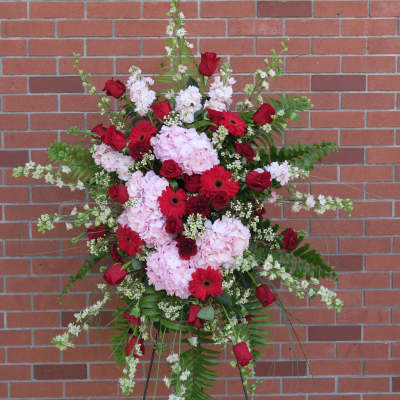 Standing floral spray with red roses, pink hydrangeas, and red gerbera daisies