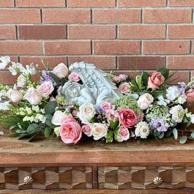 Pink and white rose arrangement with a sleeping angel statue