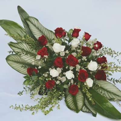 Red and white rose arrangement with large patterned leaves