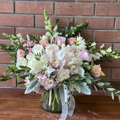 Pink and white bouquet in a glass vase with trailing greenery