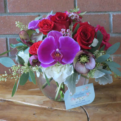 Bouquet of red roses and purple orchids in a glass vase