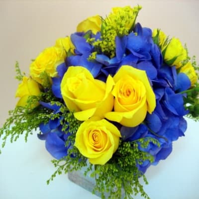 Yellow roses and blue hydrangeas arranged in a compact bouquet
