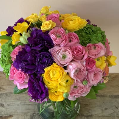 Bright bouquet of pink, yellow, and purple flowers in a glass vase