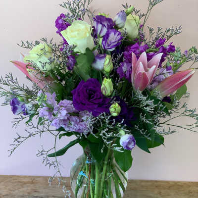 Purple and pink bouquet with roses and lilies in a glass vase