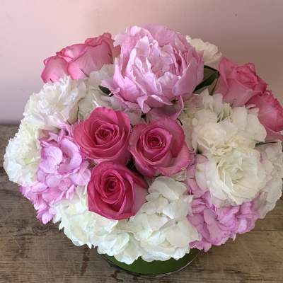 Pink roses and white hydrangeas arranged in a low round container