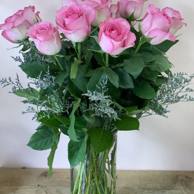 Pink roses arranged in a clear glass vase with airy filler flowers