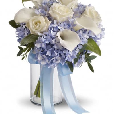 White roses and calla lilies in a glass vase with blue ribbon