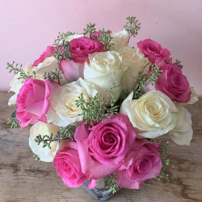 Pink and white roses arranged in a clear glass vase